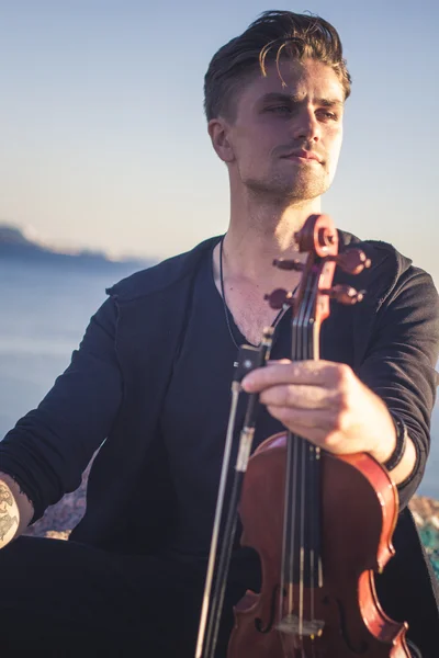 Handsome young man violinist over picturesque background — Stock Photo, Image