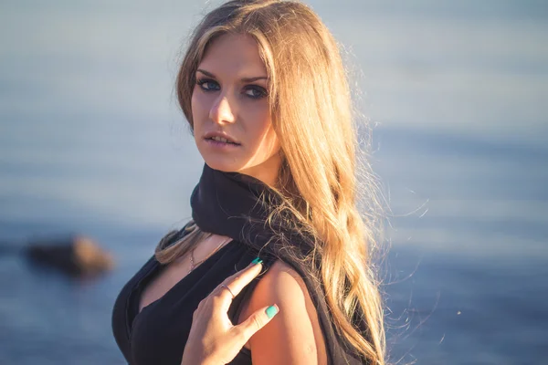 Mooie jonge blonde vrouw in een zomeravond op zee baai achtergrond — Stockfoto