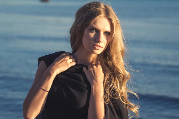 Pretty young blonde woman in a summer evening over sea bay background — Stock Photo, Image