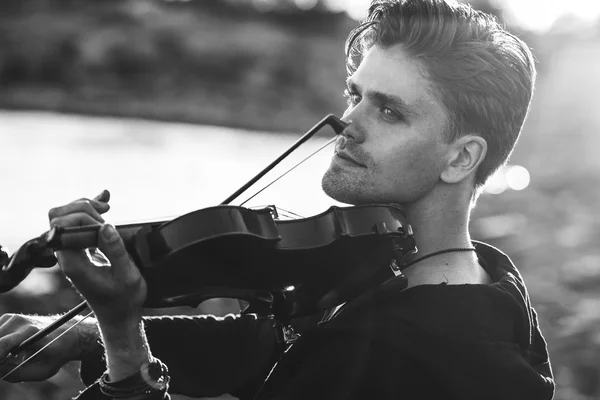 Handsome young man violinist over picturesque background — Stock Photo, Image