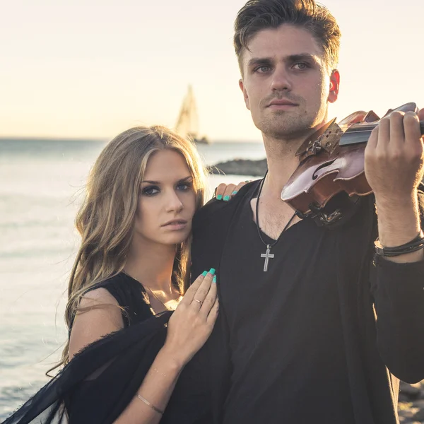 Krásný pár houslista a mladá žena dohromady u moře zálivu — Stock fotografie