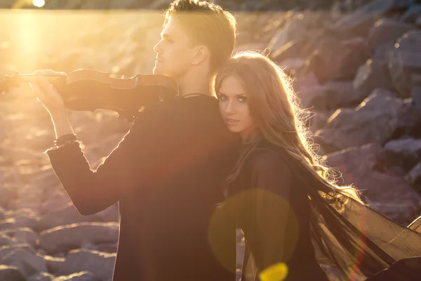 Vackra par violinist och ung kvinna tillsammans nära havet bay — Stockfoto