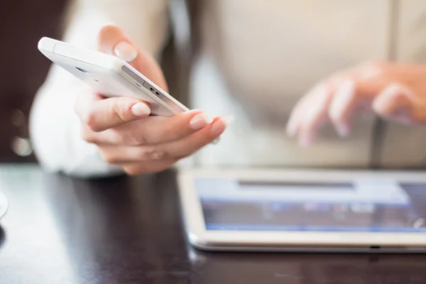 Mujer sostiene un teléfono inteligente, trabaja en la tableta digital, enfoque suave, primer plano — Foto de Stock