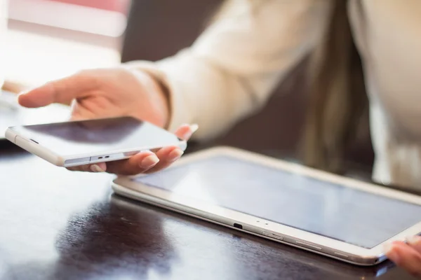 Mujer sostiene un teléfono inteligente, trabaja en la tableta digital, enfoque suave, primer plano — Foto de Stock