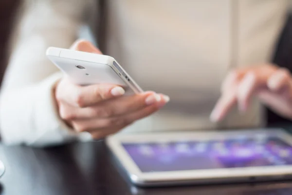 Mujer sostiene un teléfono inteligente, trabaja en la tableta digital, enfoque suave, primer plano — Foto de Stock