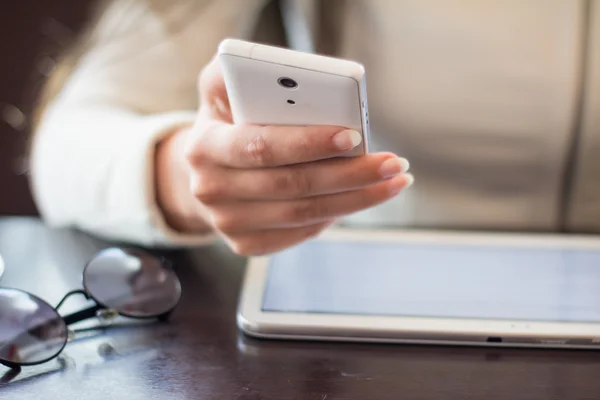 Mujer sostiene un teléfono inteligente, trabaja en la tableta digital, enfoque suave, primer plano — Foto de Stock