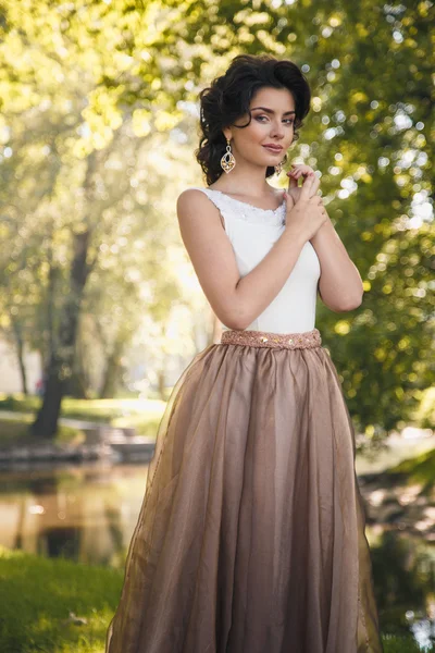 Retrato de hermosa novia elegante en vestido beige magnífico camina en un parque — Foto de Stock