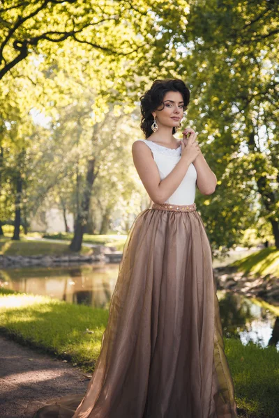 Retrato de hermosa novia elegante en vestido beige magnífico camina en un parque — Foto de Stock
