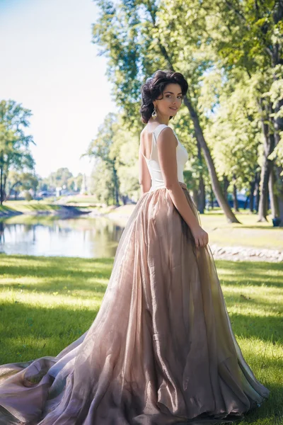 Retrato de bela noiva elegante em lindo vestido bege caminha em um parque — Fotografia de Stock