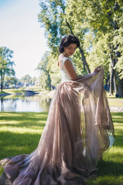 Портрет красивой элегантной невесты в великолепном бежевом платье прогулки в парке — стоковое фото