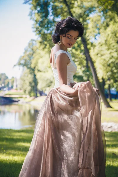 Retrato de hermosa novia elegante en vestido beige magnífico camina en un parque — Foto de Stock