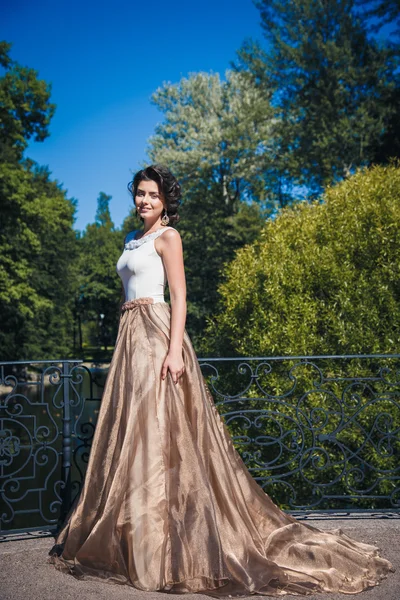 Retrato de bela noiva elegante em lindo vestido bege caminha em um parque — Fotografia de Stock