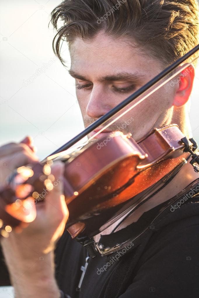 Handsome young man violinist over picturesque background