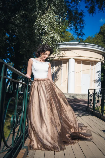 Retrato de bela noiva elegante em lindo vestido bege caminha em um parque — Fotografia de Stock