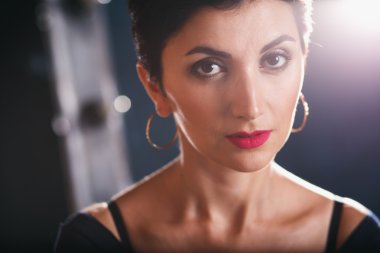 Close-up portrait of gorgeous woman with short black hair and long earrings