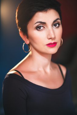 Close-up portrait of gorgeous woman with short black hair and long earrings