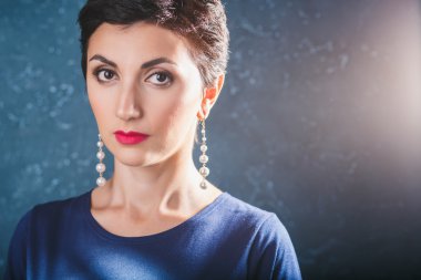 Close-up portrait of gorgeous woman with short black hair and long earrings