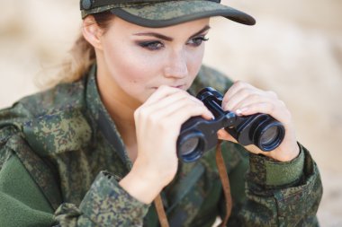 Güzel genç kadın bir tatlı arka plan üzerinde bir dürbün ile askeri bir kostüm