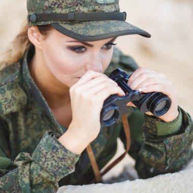 Güzel genç kadın bir tatlı arka plan üzerinde bir dürbün ile askeri bir kostüm