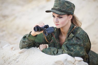 Güzel genç kadın bir tatlı arka plan üzerinde bir dürbün ile askeri bir kostüm