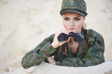 Güzel genç kadın bir tatlı arka plan üzerinde bir dürbün ile askeri bir kostüm
