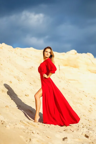 Preciosa mujer joven cabeza roja en vestido largo rojo en un postre. Sandy Canyon. Estilo de moda — Foto de Stock