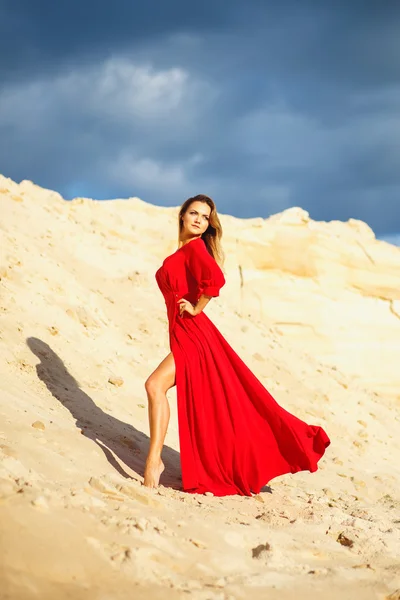 Preciosa mujer joven cabeza roja en vestido largo rojo en un postre. Sandy Canyon. Estilo de moda — Foto de Stock