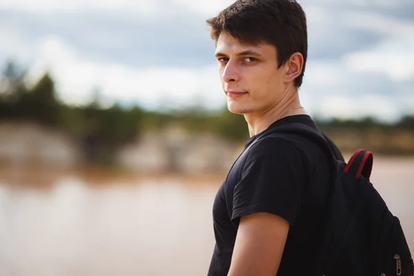 Egy csinos, fiatal férfi fekete ruhát, a háttérben egy tó, egy nyári nap — Stock Fotó
