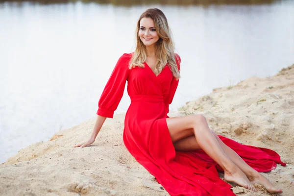 Preciosa mujer joven cabeza roja en vestido largo rojo sobre un fondo de un lago. Sandy Canyon. Estilo de moda —  Fotos de Stock