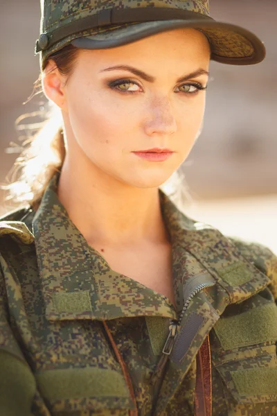 Gorgeous young woman in a Military costume on the background of a dessert