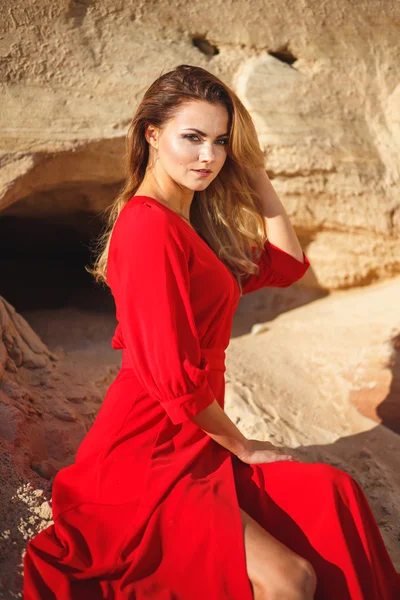 Gorgeous red head young woman in long red dress in a dessert. Sandy canyon. Fashion style — Stock Photo, Image