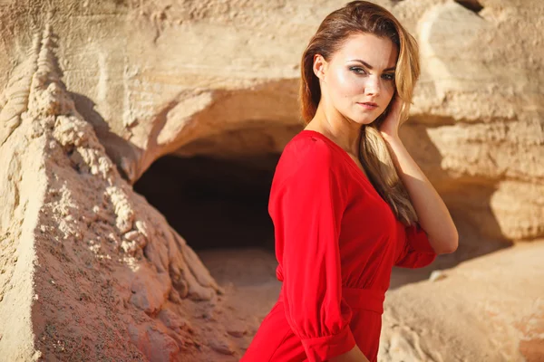 Gyönyörű vörös fej fiatal nő, hosszú piros ruha a desszert. Sandy canyon. Divat-stílus — Stock Fotó