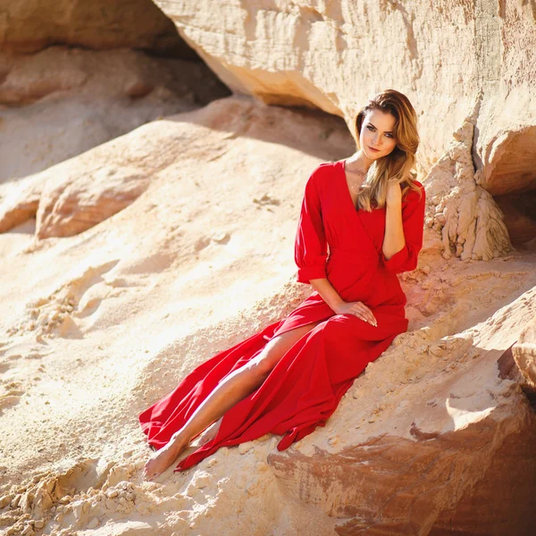 Underbara röda huvud ung kvinna i lång röd klänning i en dessert. Sandy canyon. Klädstil — Stockfoto