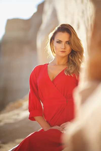 Gorgeous red head young woman in long red dress in a dessert. Sandy canyon. Fashion style — Stock Photo, Image