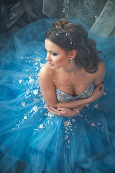 Mooie jonge vrouw in prachtige blauwe lange jurk zoals Assepoester met perfecte make-up en haar stijl — Stockfoto