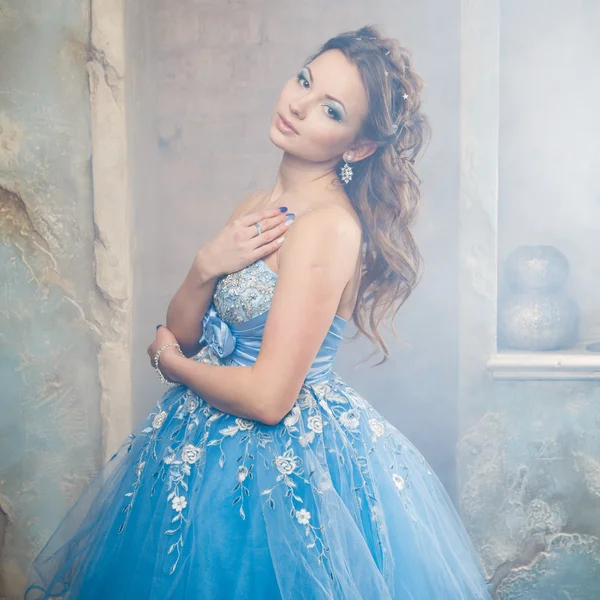 Όμορφη νεαρή γυναίκα σε πανέμορφο μπλε μακρύ φόρεμα όπως η Σταχτοπούτα με τέλειο μακιγιάζ και στυλ μαλλιών — Φωτογραφία Αρχείου