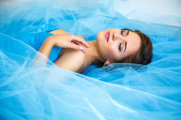 Beautiful bride lying on gorgeous blue dress Cinderella style in a morning — Stok fotoğraf