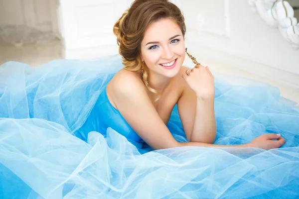 Beautiful bride lying on gorgeous blue dress Cinderella style in a morning — стокове фото