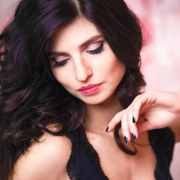 Portret van mooie brunette vrouw met perfecte make-up en haarstijl op achtergrond met bloemen — Stockfoto
