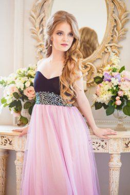 Portrait of pretty young girl in a nice dress and long blonde hair in gorgeous interior