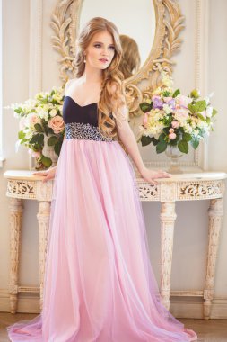 Portrait of pretty young girl in a nice dress and long blonde hair in gorgeous interior