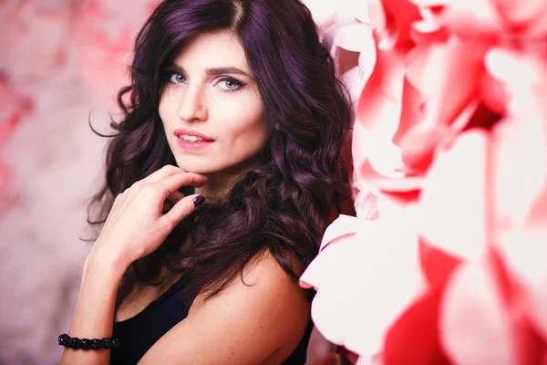 Portrait of beautiful brunette woman with perfect make up and hair style over background with flowers — Stock Photo, Image