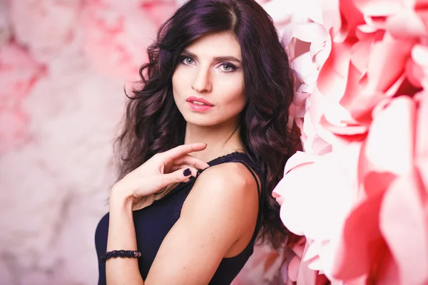 Portrait of beautiful brunette woman with perfect make up and hair style over background with flowers — Stock Photo, Image