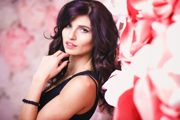 Portret van mooie brunette vrouw met perfecte make-up en haarstijl op achtergrond met bloemen — Stockfoto