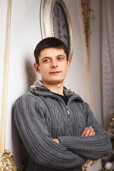 Retrato de un joven en jersey gris sobre fondo navideño — Foto de Stock