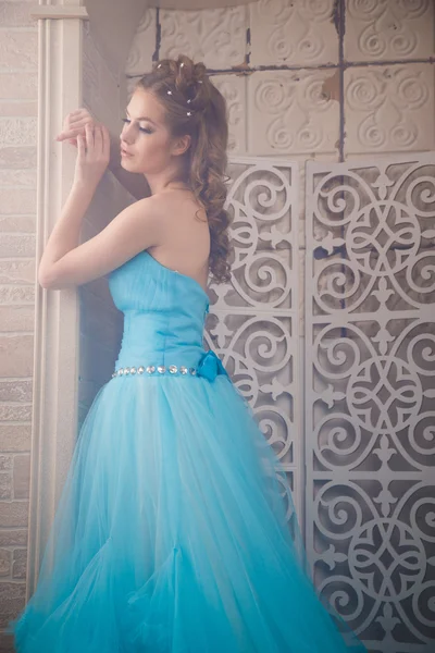 Красивая молодая женщина в великолепном голубом длинном платье, как Золушка с идеальным макияжем и прической — стоковое фото