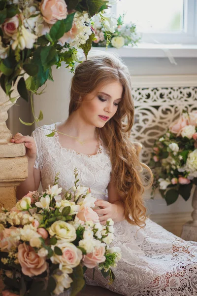 Portrait of pretty young girl in a white dress and long blonde hair surrounded by flowers — Stok fotoğraf