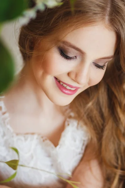 Portrait of pretty young girl in a white dress and long blonde hair surrounded by flowers — Stockfoto