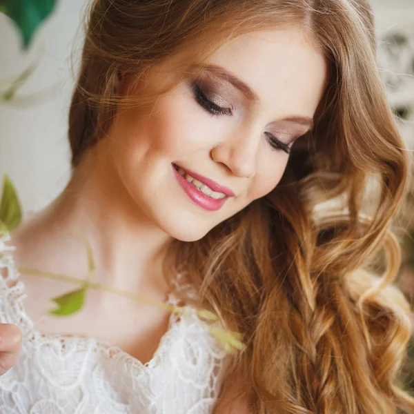 Portrait of pretty young girl in a white dress and long blonde hair surrounded by flowers — Stockfoto