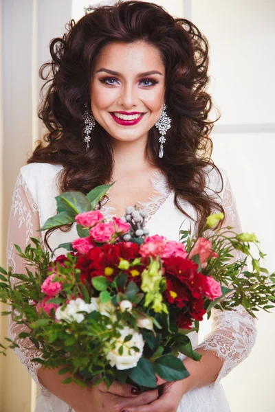 Close-up portrait of gorgeous beautiful bride in white dress with amazing hair style and make up, holding bouquet — Stock Fotó